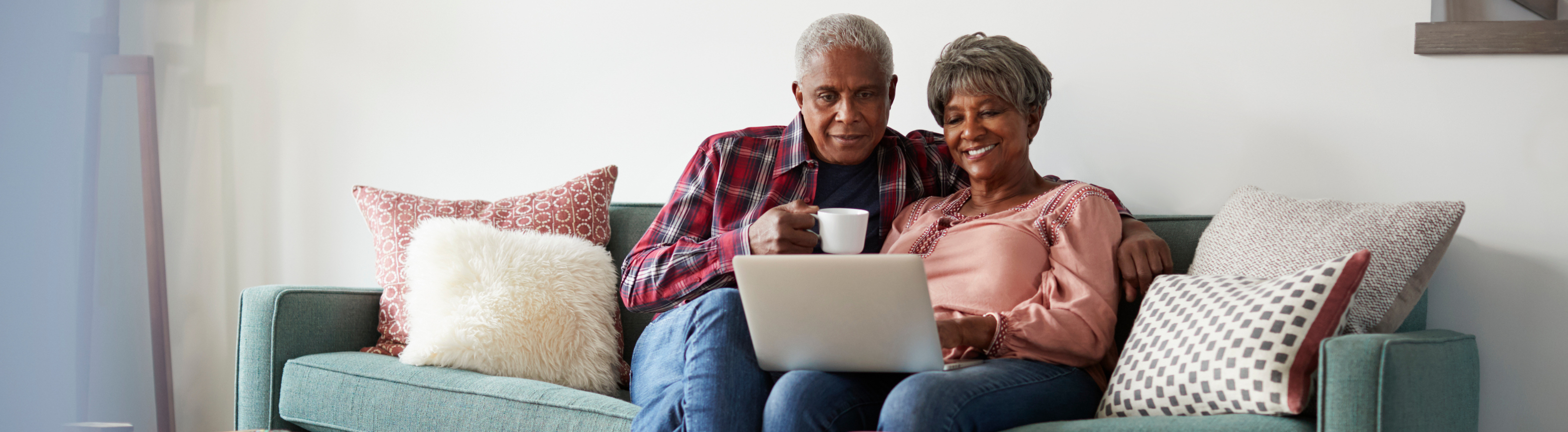 Older adults looking at content on laptop sitting on couch